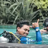 Dive instructor in a swimming pool giving the "that rocks" signal