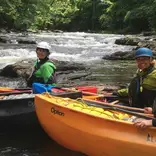 Crew in kayaks on a white water river, on the river bank look over for a picture.