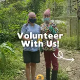 Two volunteers surrounded by jungle and enclosures in our pre-release area giving a thumbs-up 