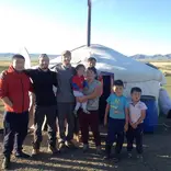 Volunteers and nomads are standing in front of the Mongolian traditional dwelling.