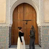 Two students standing in front of a wooden, carved door in the Medina