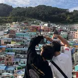 Students making heart hands over Busan skyline
