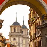 Red archway looking out on historic building in Spain