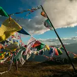 Prayer flags flying in the wind in the mountains of Bhutan with large clouds above in a light blue sky