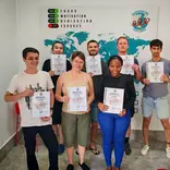 TEFL trainees holding certificates during graduation ceremony in training classroom.