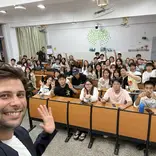 Smiling male TEFL teacher takes a selfie with a classroom full on students.