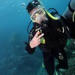 Jayden in Australia scuba diving underwater, wearing diving gear and posing his fingers in deuces