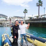 divers in wetsuits standing on a dinghy