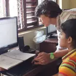 volunteer helping child with computer program in Sri Lanka