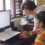 volunteer helping child with computer program in Sri Lanka
