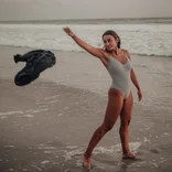 girl throws her shirt as she gets into the ocean