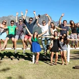 group of students jumping with mountains behind them