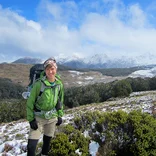 student wearing hiking gear smiling with mountains behind her