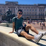 student sitting on a ledge in front oh Buckingham Palace in London