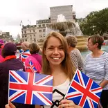 student in a parade crowd holding two Union Jack flags