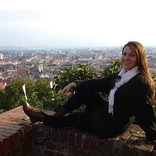student laying on a ledge, posing for picture, in front of the Vienna skyline