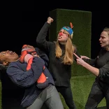 three students acting with props