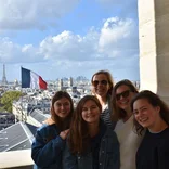 Group of students standing on a balcony with the Paris skyline and Eiffel Tower behind them