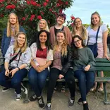 group of students sitting on and standing behind a bench in a park in Paris