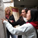three students gathered around a stone slab with inscribed text in Rome
