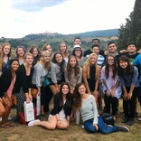 large group of students standing in front of the hilly Tuscan landscape with the city in the distance on the horizon