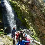 A student group stands in front of a waterfall.