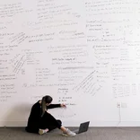 A student brainstorms her business analytics assignment on a whiteboard