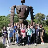 Students posing near robot statue in park in Tokyo