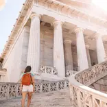 Student walking up steps of historical building in Athens