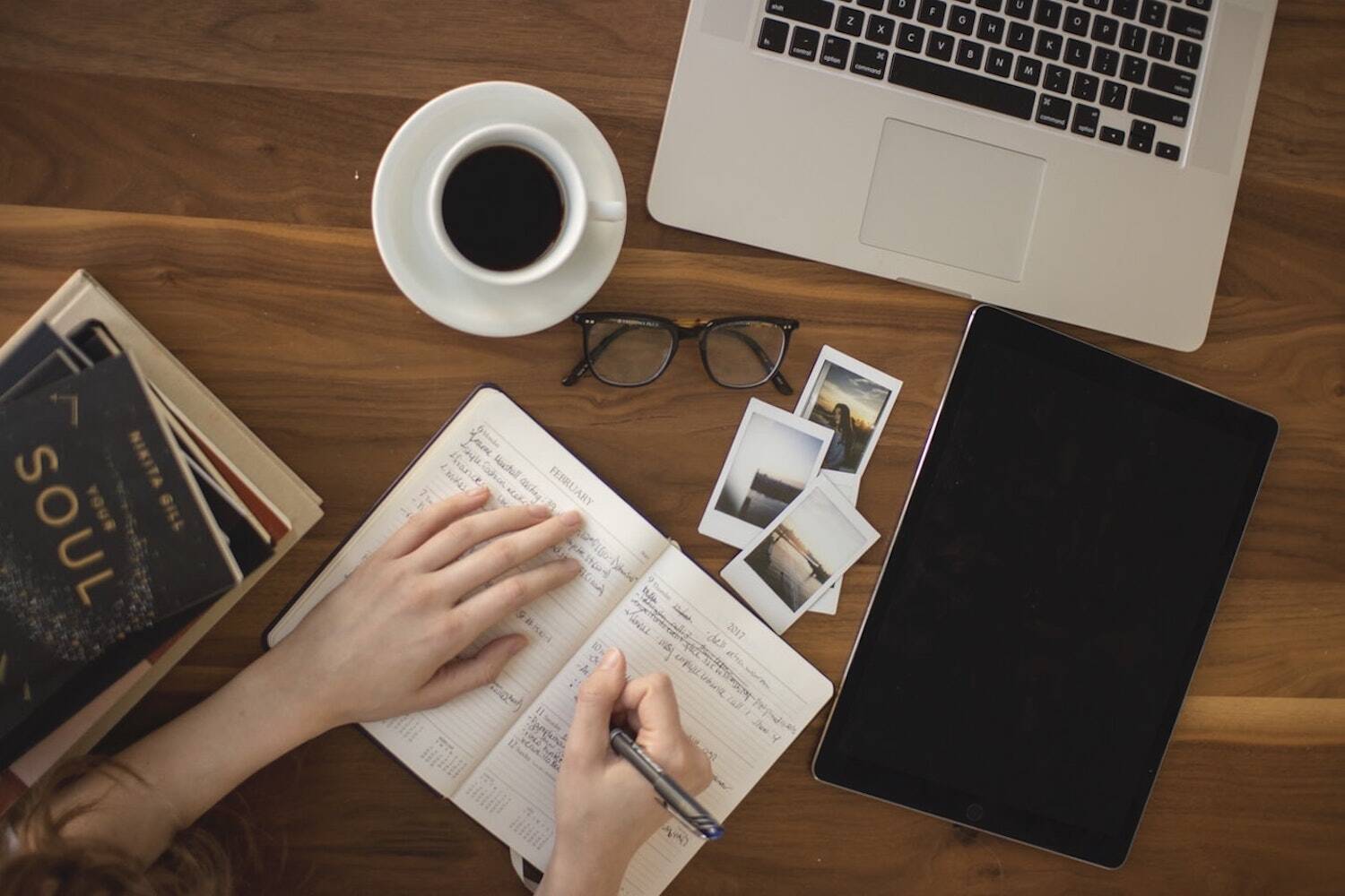 aerial view of desk with woman writing on notebook
