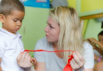 Volunteer assisting a young boy with his ribbon in Ecuador