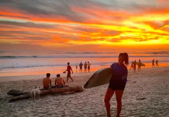 woman with surfboard at sunset on beach