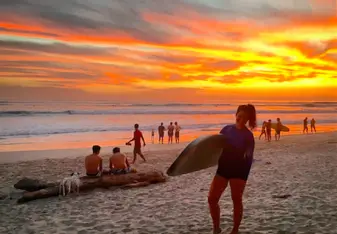woman with surfboard at sunset on beach