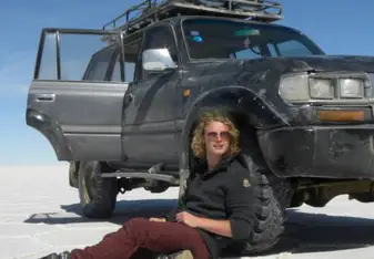 man sitting next to 4wd in desert