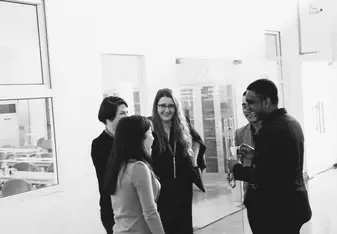 black and white of five adults standing in office