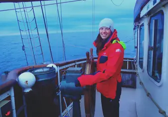 woman in bright coat at helm of ship