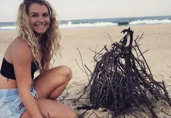 woman smiling next to campfire on beach