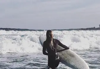 woman carrying surf in white water