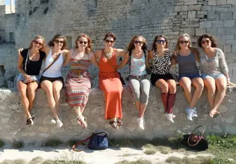 group of women sitting on stone wall