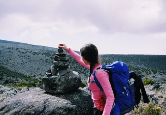 woman with backpack stacking rocks