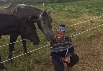 intern posing outside in ecuador next to horse