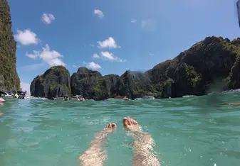 swimming in clear water with view of cliffs