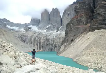 man by turquoise lake in mountains