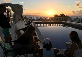 young people relaxing buy pool at sunset