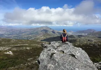 woman sitting on rock overlooking valley
