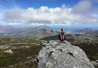 woman sitting on rock overlooking valley