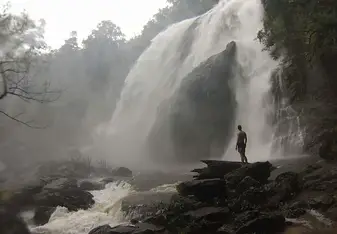 man standing under waterfall