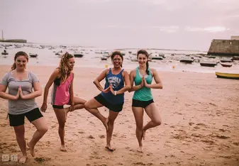 female group doing yoga on beach