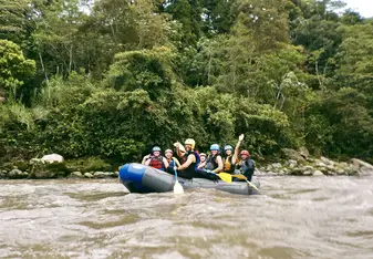 Students white water rafting down a murky river in the jungle near Baños