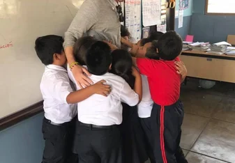 teacher hugging students in classroom